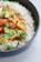 A bowl of steaming white rice served with fresh vegetables.