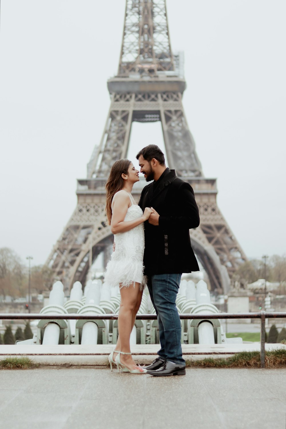 a man and woman standing in front of the eiffel tower