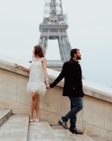 a man and a woman holding hands near the eiffel tower