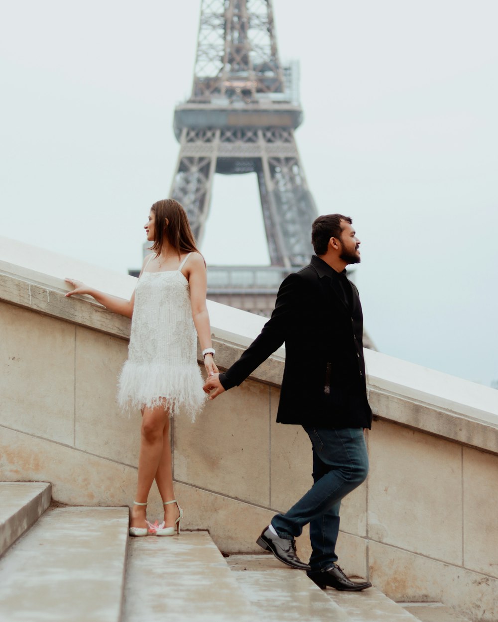 a man and a woman holding hands near the eiffel tower