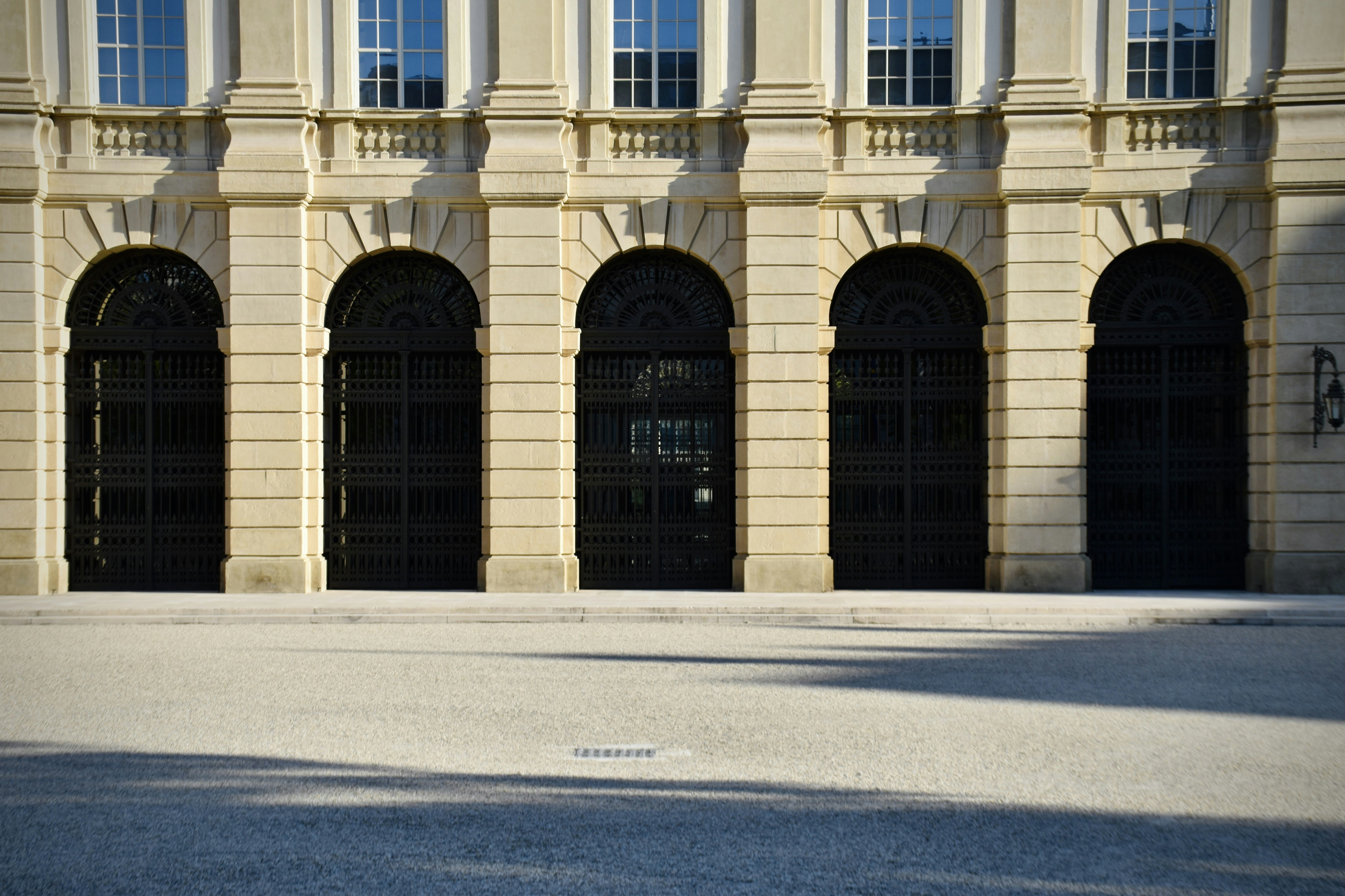 a man riding a skateboard down a street next to a tall building, Palais Liechtenstein in Vienna, a truly grand palace with a large public garden, therefore also called Gartenpalais. It was built by the Liechtenstein family in 1700. Albeit Liechtenstein is known as a micro-country and tax-haven, its ties go back a long time to the Habsburgian austro-hungarian monarchy, hence tow distinct Liechtenstin Palaces exist in Vienna, the other being the Stadtpalais (town palace) in the center close to Hofburg and Burgtheater.