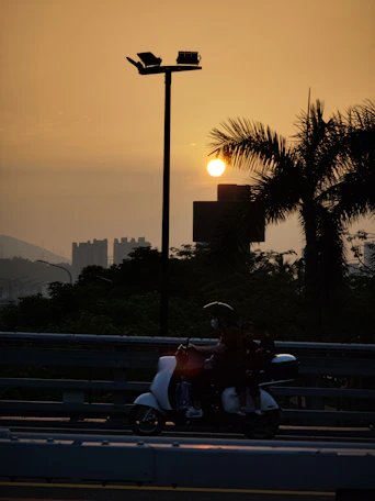 Photo of a delivery person on a motorbike navigating through Santana do Ipanema streets during sunset