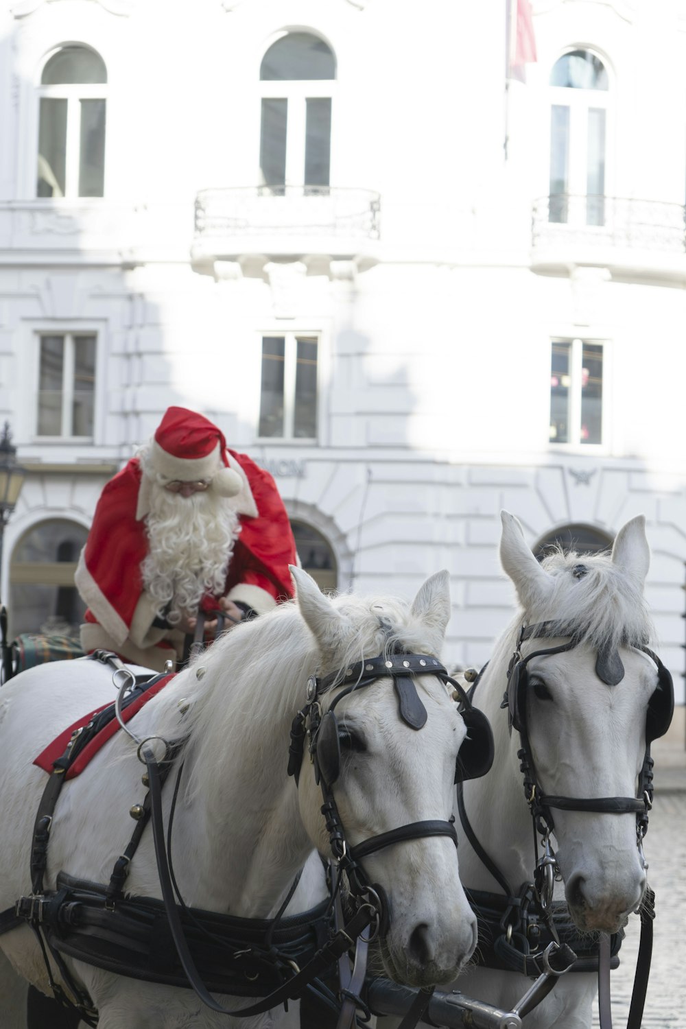 a man dressed as santa claus riding on a horse drawn carriage