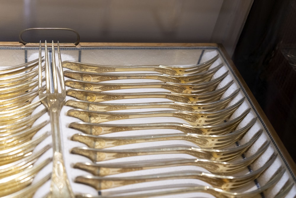 a bunch of gold colored forks and spoons in a box