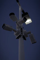 Security cameras and bright spotlights illuminating the storage facility at dusk.