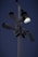 Several security cameras are mounted on a tall pole, with a bright light fixture attached nearby. The background is a dark evening sky.