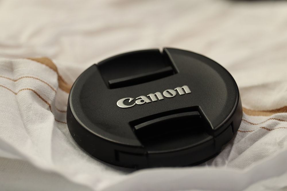 a canon lens cap sitting on top of a white blanket
