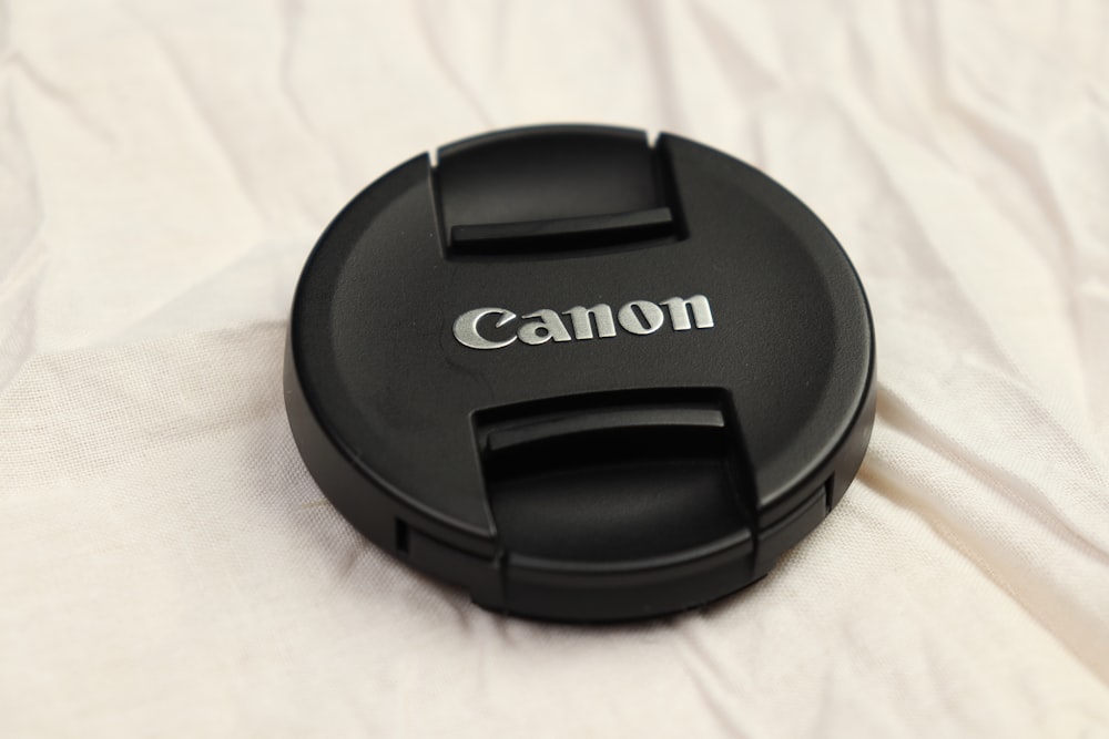 a canon lens cap sitting on top of a white sheet