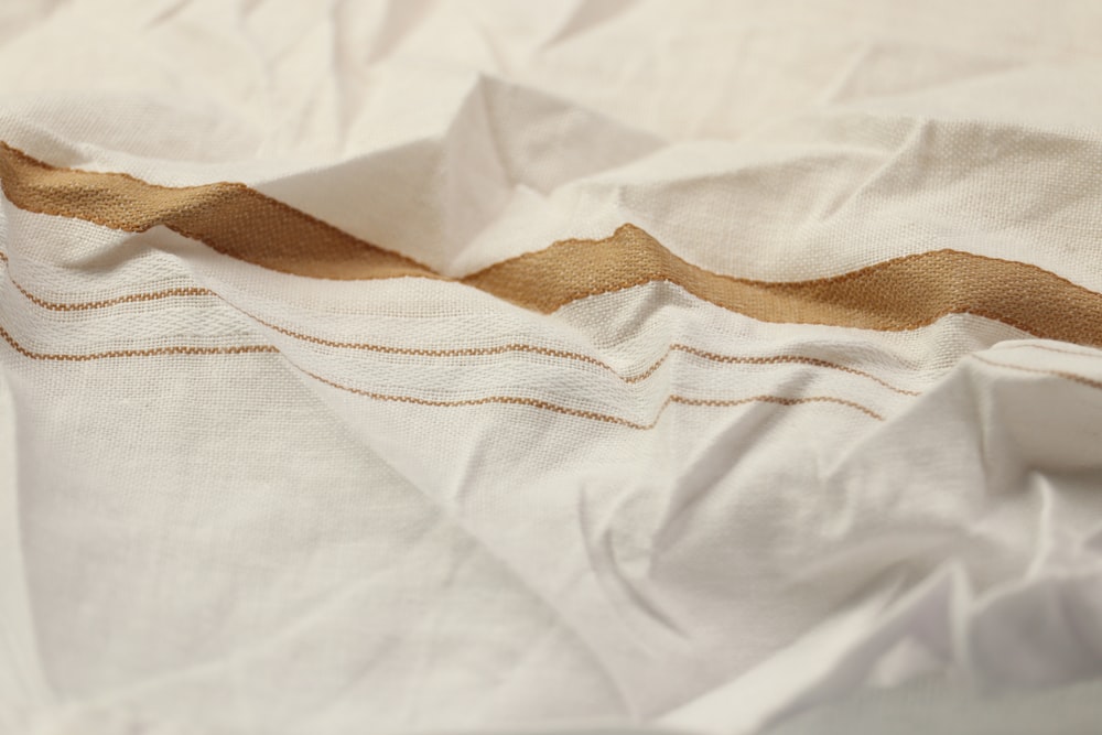 a close up of a bed with a white and gold comforter