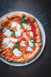 A crispy golden pizza topped with fresh tomatoes, basil, and mozzarella.