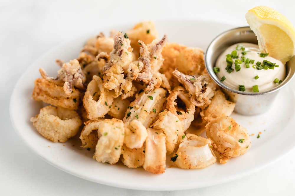 a white plate topped with fried food and a dipping sauce