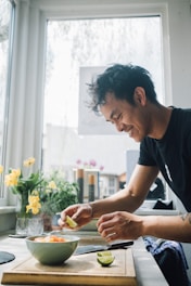 A cheerful person preparing a colorful, balanced meal in a cozy kitchen filled with natural light.