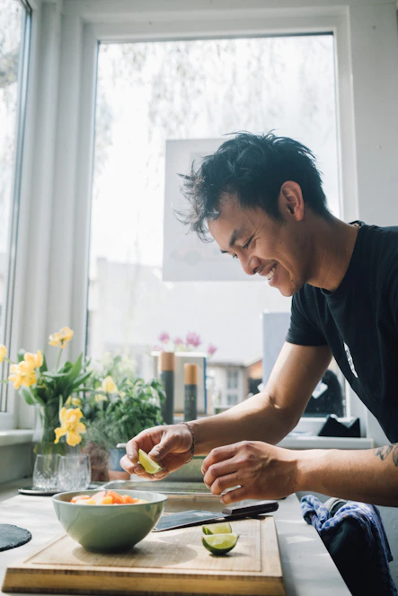 A cheerful cook swiftly chopping vegetables in a bright kitchen.