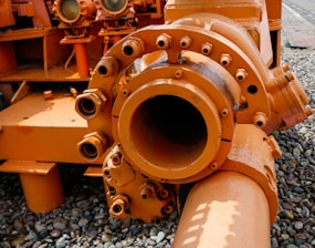 a large orange pipe laying on top of a gravel field