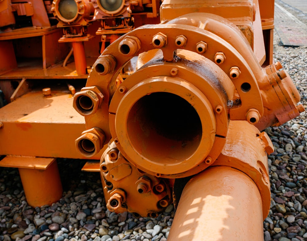 a large orange pipe laying on top of a gravel field