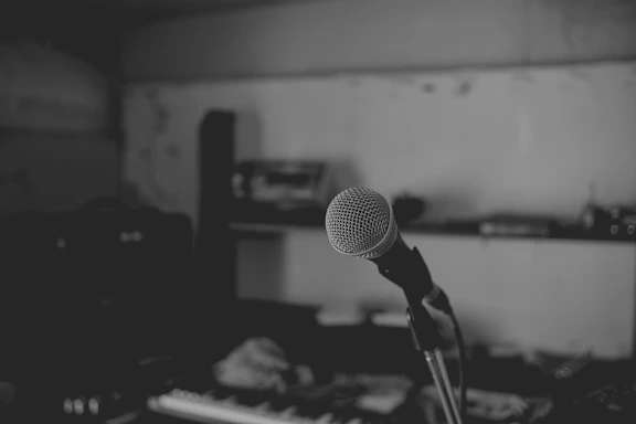 A sleek black and white photo of a vintage microphone on a minimalist desk.