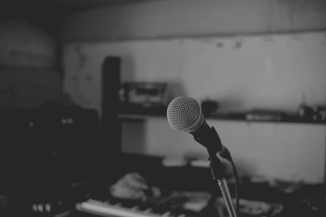 A sleek, moody studio shot featuring vintage microphones and silver soundboards bathed in charcoal lighting.