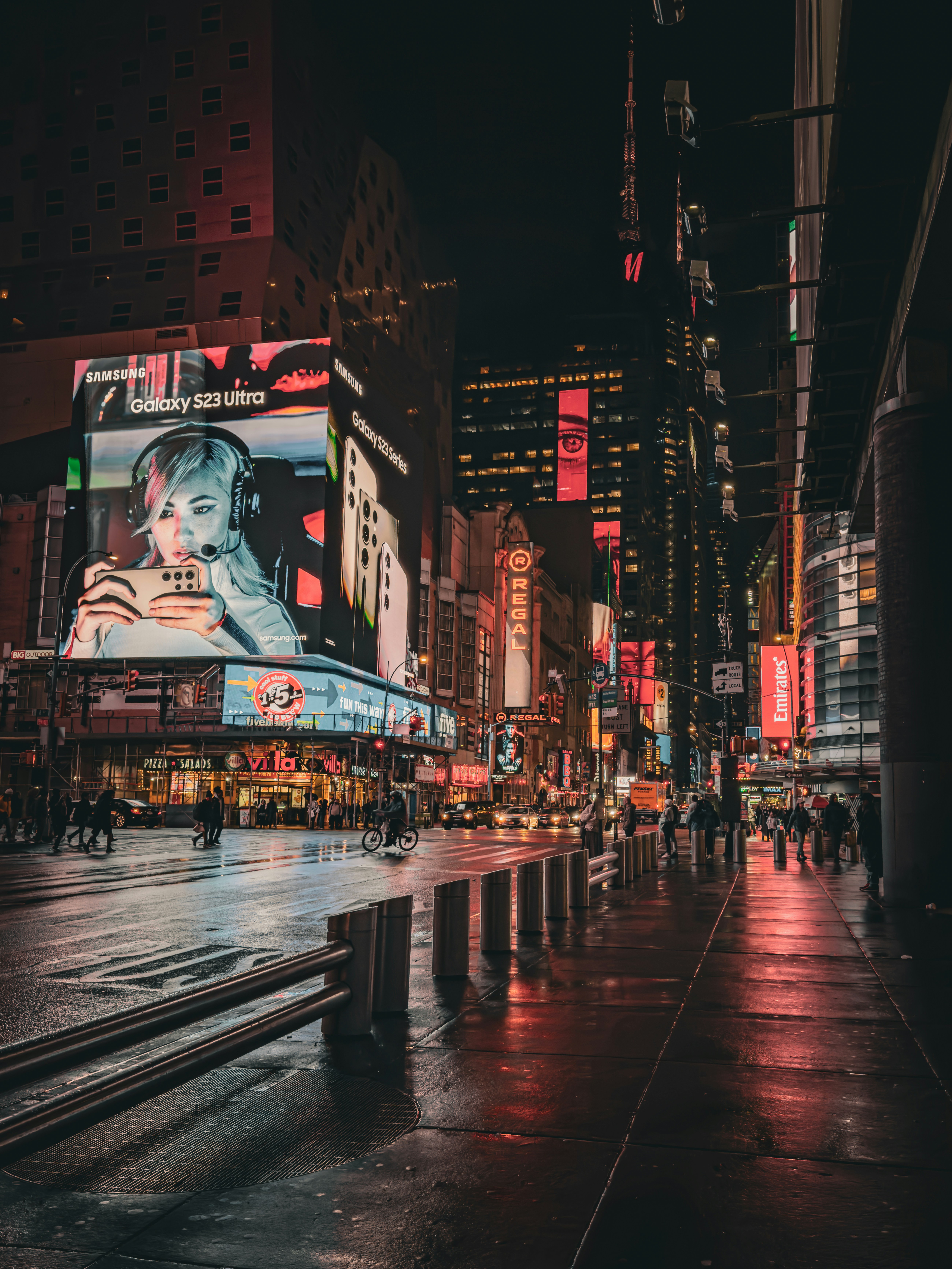 a city street at night with people walking on the sidewalk