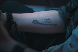 Close-up of a black ink tattoo featuring intricate musical notes on forearm