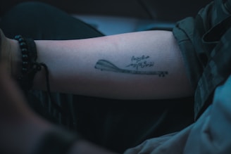 Close-up of a black ink tattoo featuring intricate musical notes on forearm