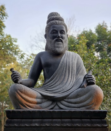 A serene portrait of Kala Bahirava Ji seated calmly with ancient astrology charts and palm reading tools.