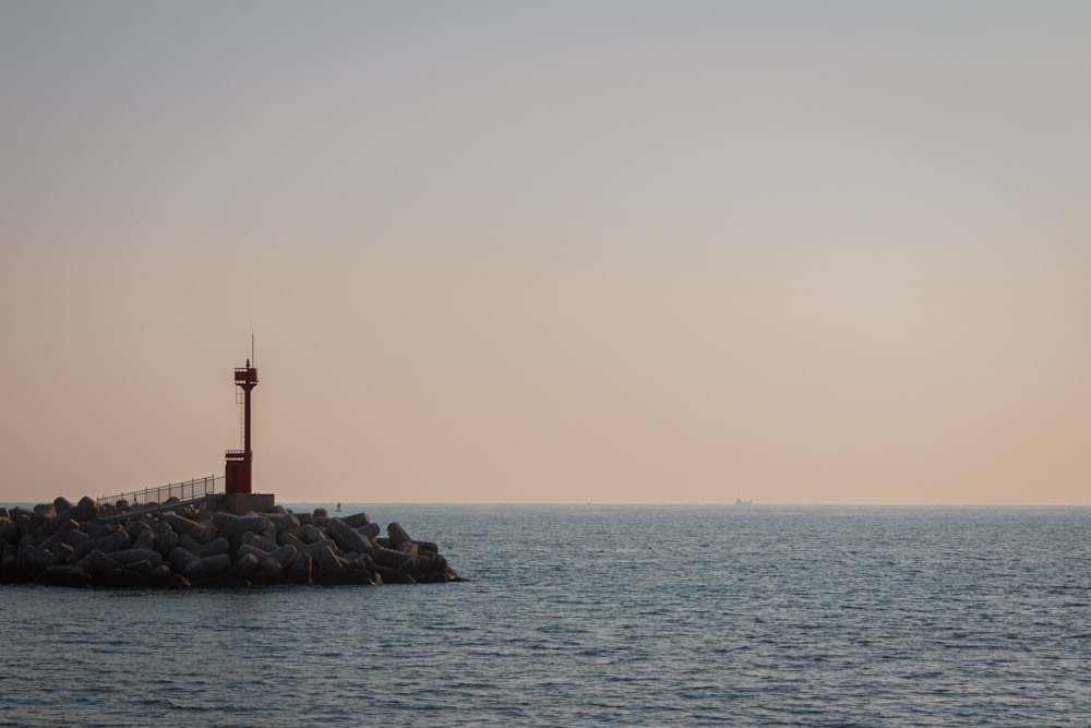 a lighthouse on a rock outcropping in the middle of the ocean