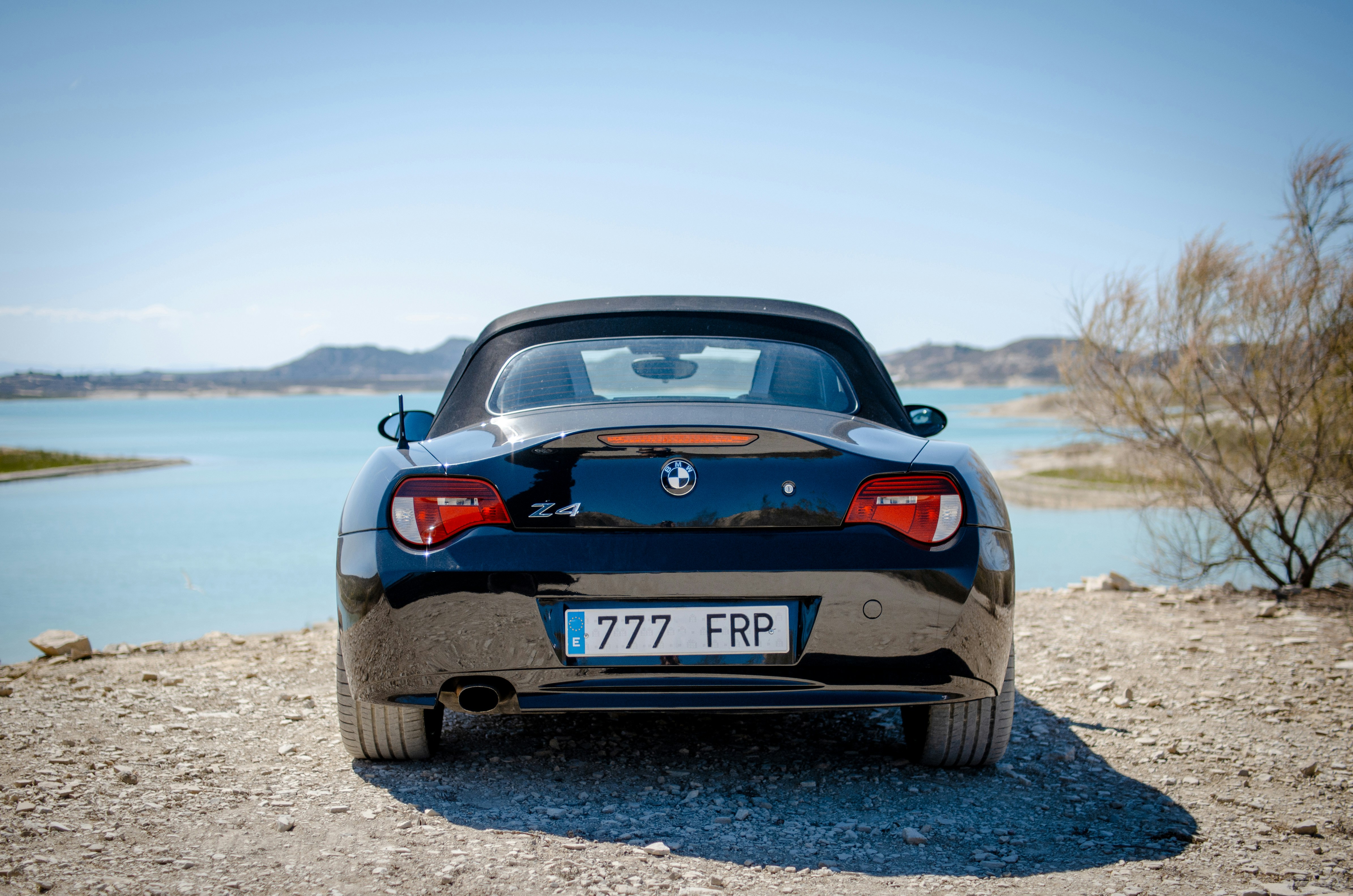 the back end of a sports car parked on a gravel road