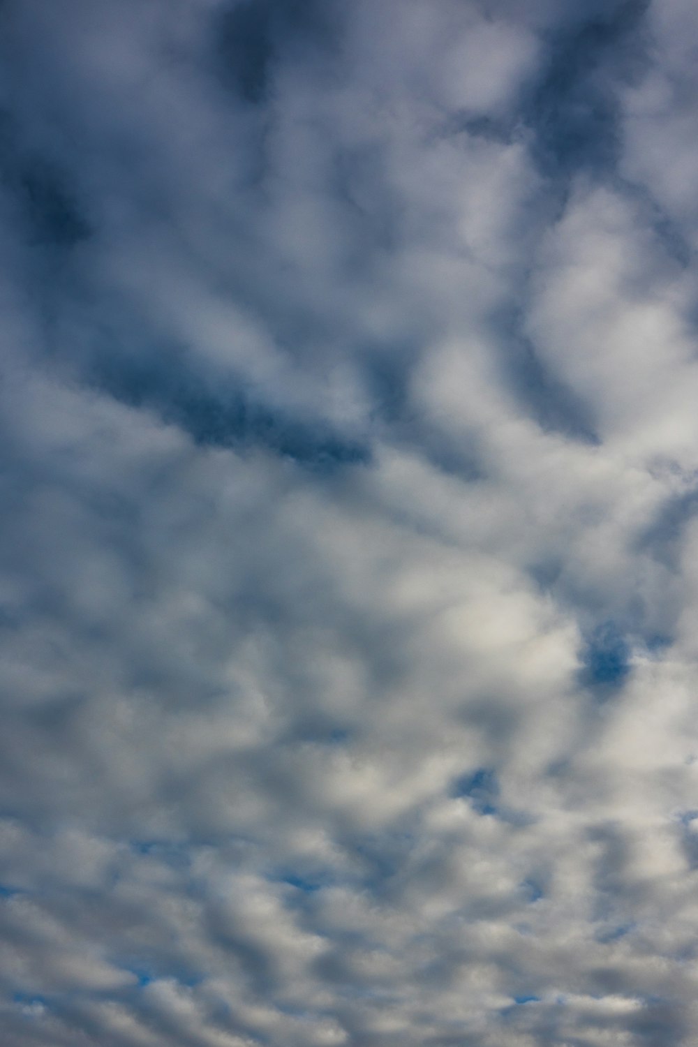 a plane flying through a cloudy blue sky