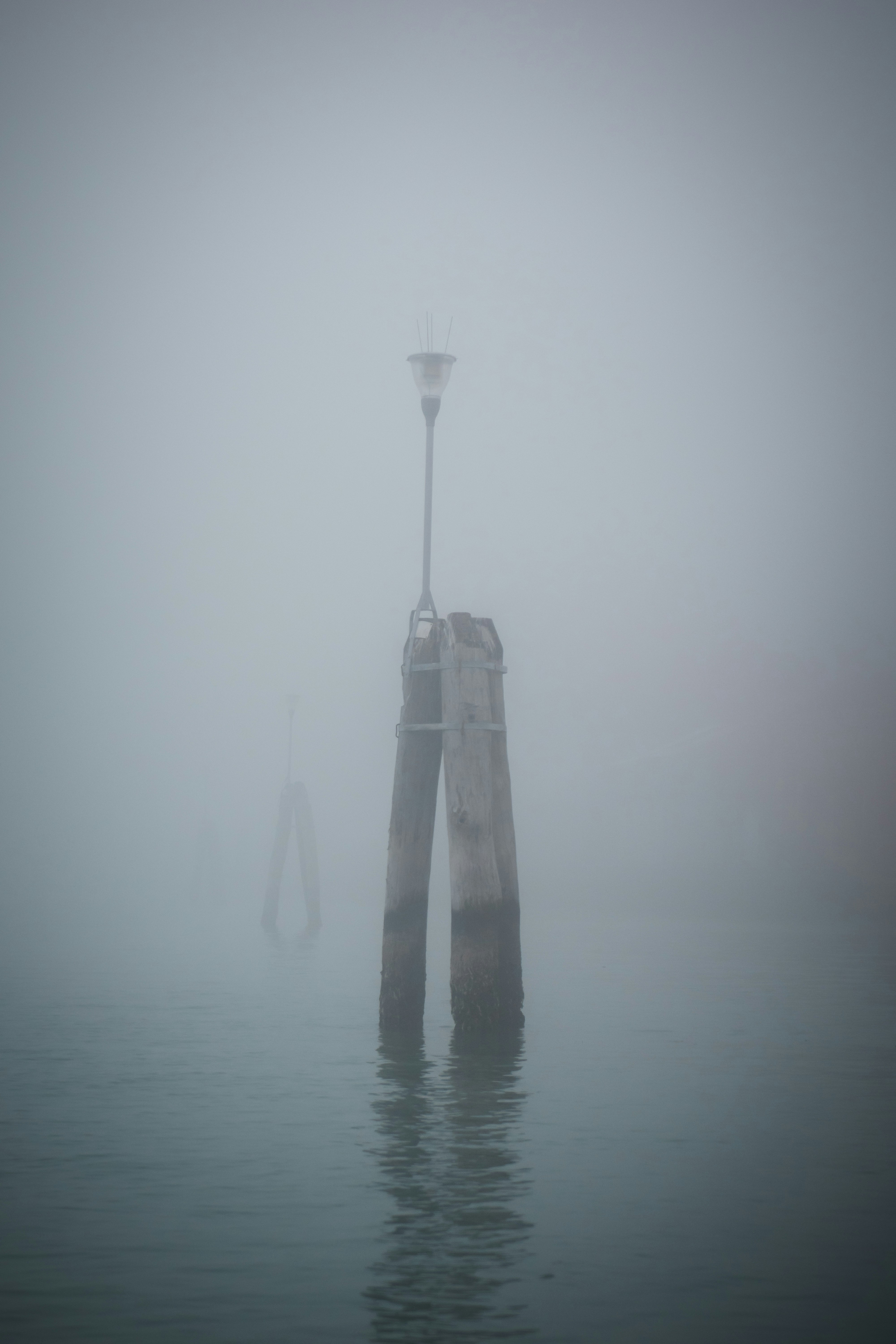 물 한가운데에 전등 기둥이 있는 안개 낀 날