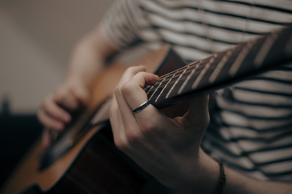 a person holding a guitar and playing the guitar