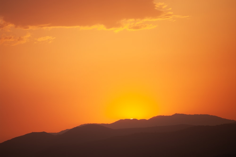 the sun is setting over a mountain range