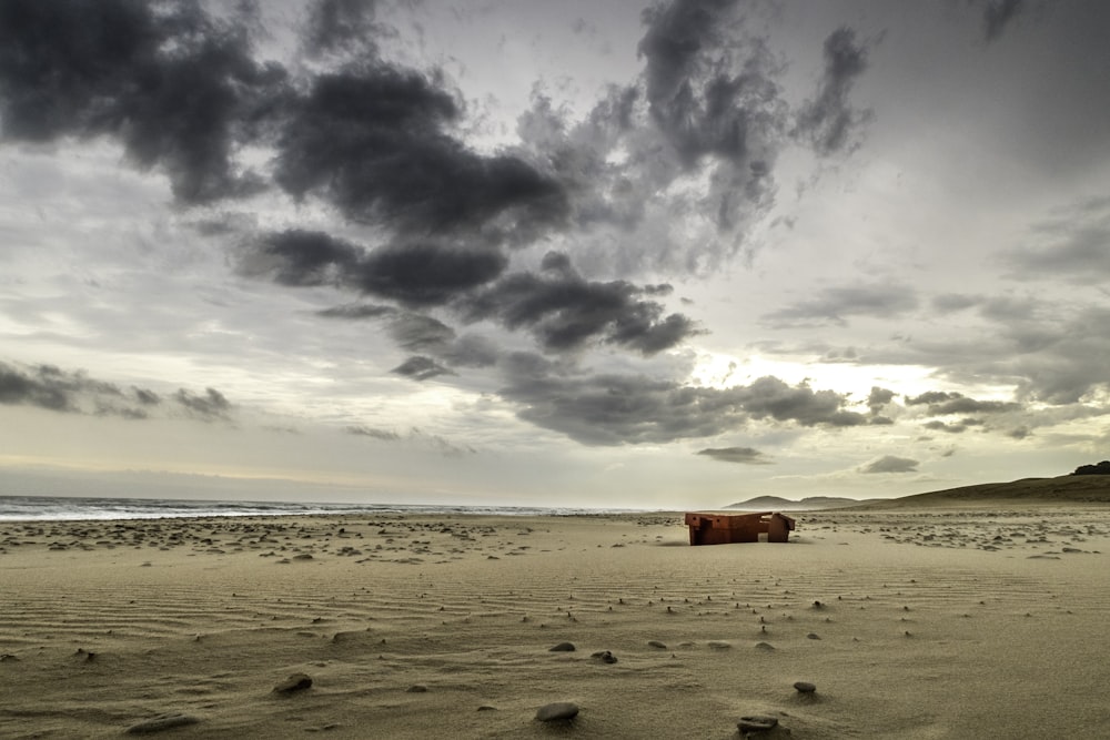 a cloudy sky over a beach with a boat in the distance
