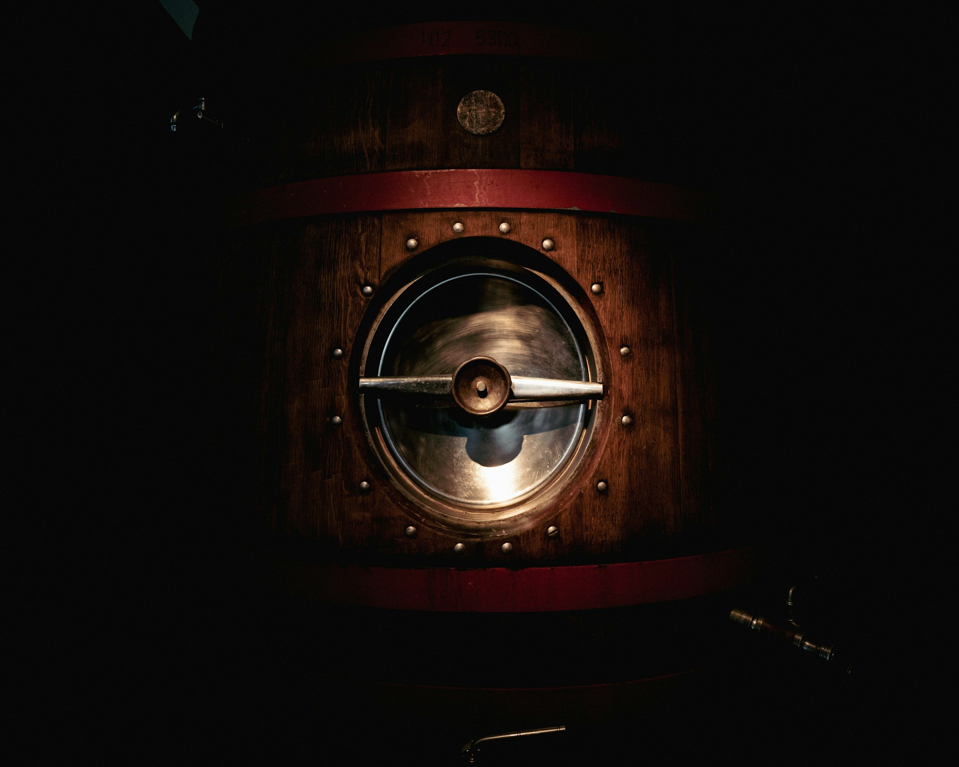 a dark room with a metal door and a wooden barrel