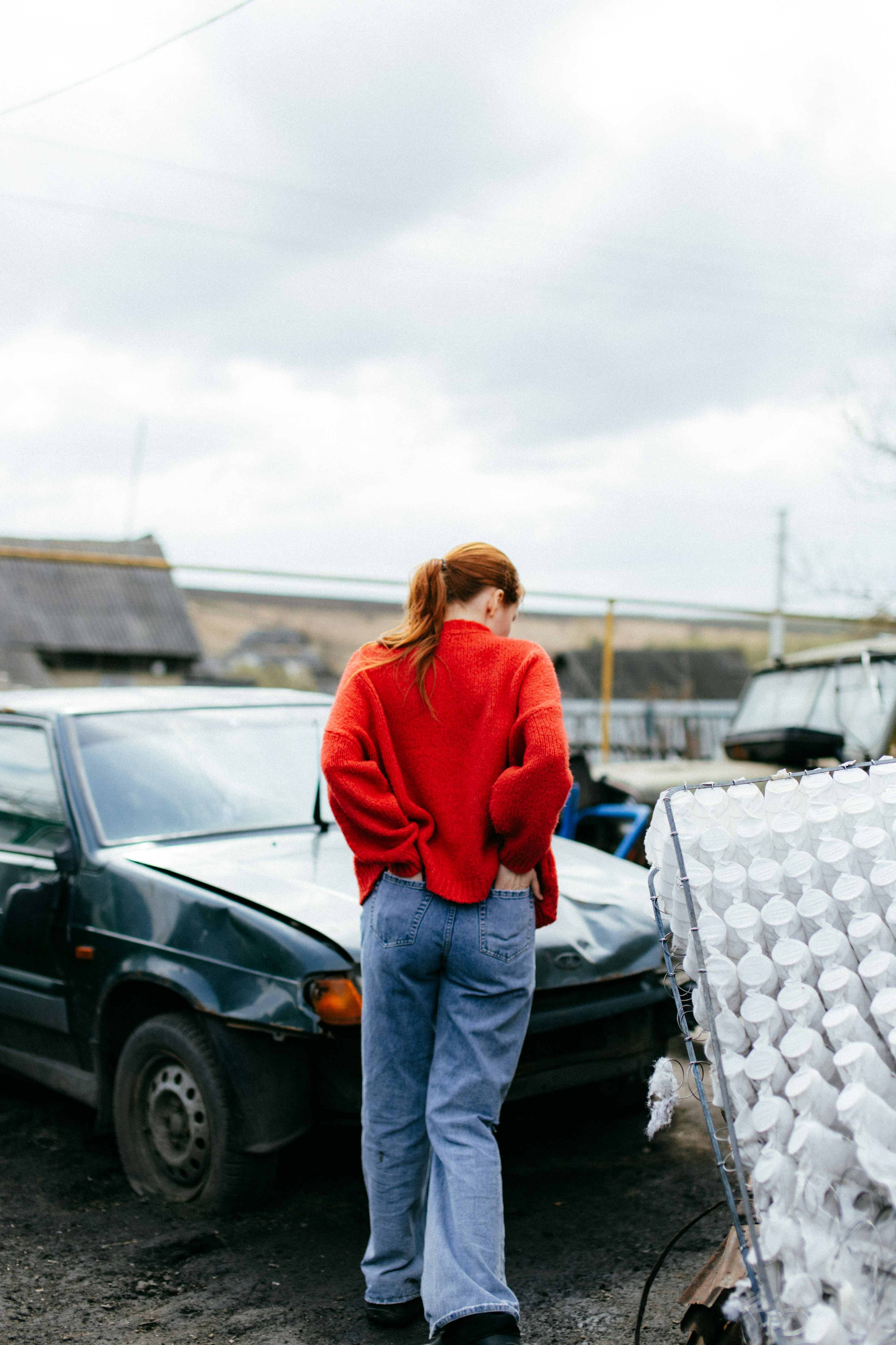 a woman in a red sweater is standing next to a car