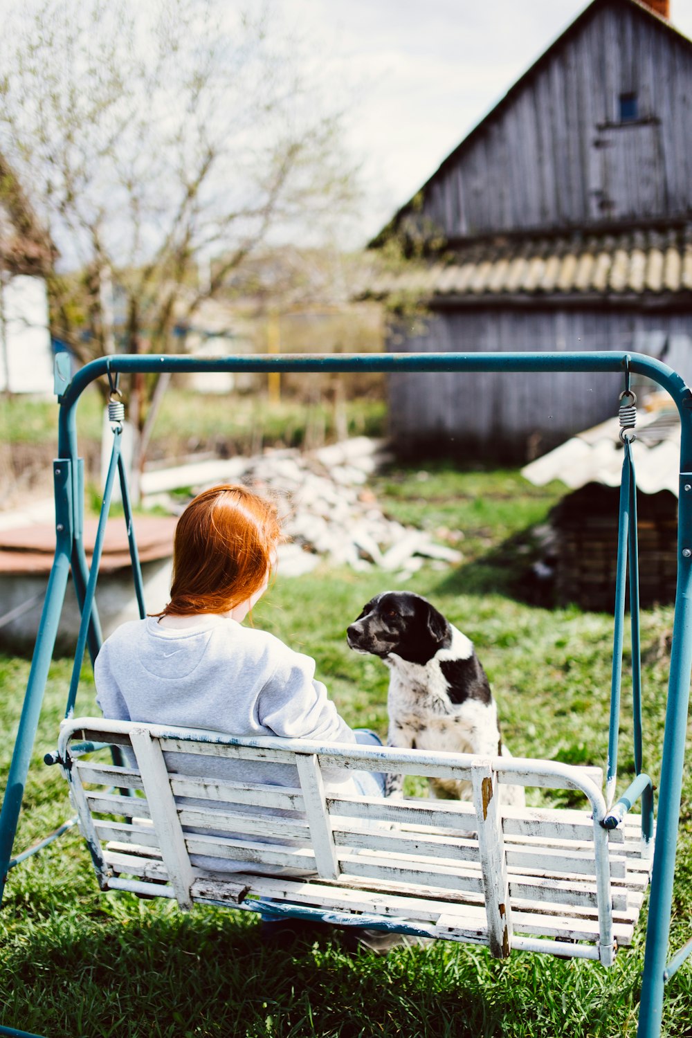 a woman sitting on a swing with a dog