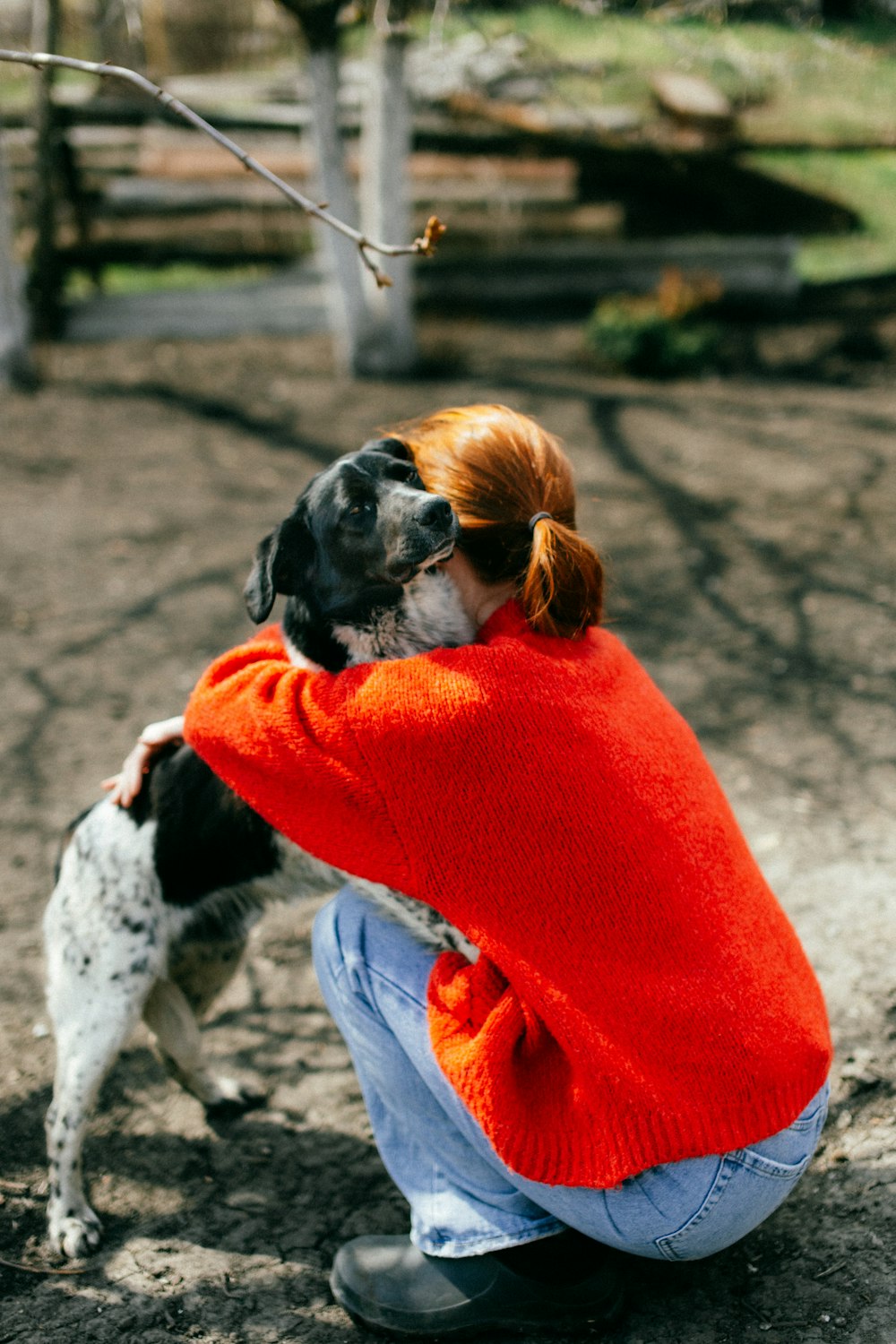 a woman in a red sweater hugging a black and white dog