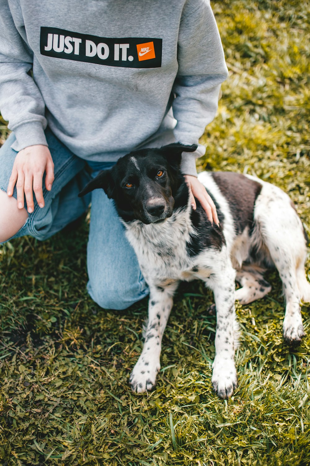 a woman kneeling down next to a black and white dog