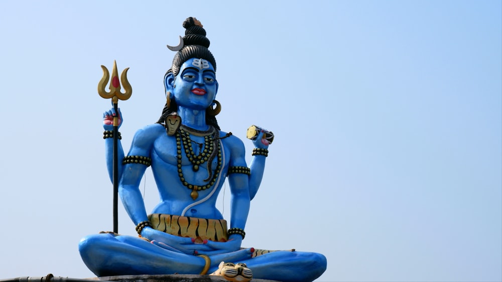 Una statua di un dio indù che tiene un bastone