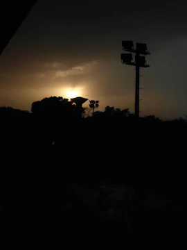 A dramatic silhouette of a lighting rig against a twilight sky.