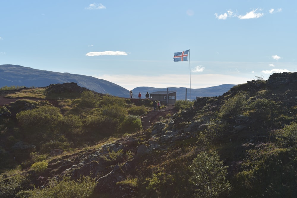 a flag on top of a hill with mountains in the background