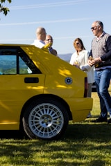 A happy family standing next to their new car in a sunny driveway.