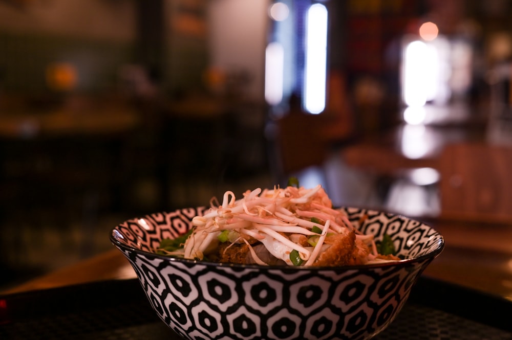 a black and white bowl filled with food on top of a table