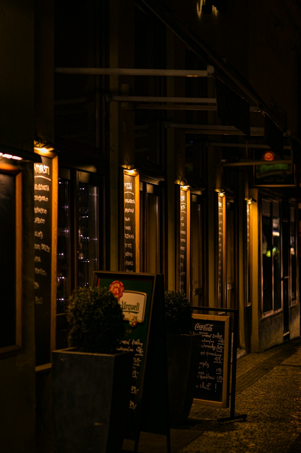 a dark street at night with a sign and potted plants