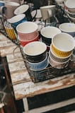 A collection of colorful handmade mugs arranged on a rustic wooden table.