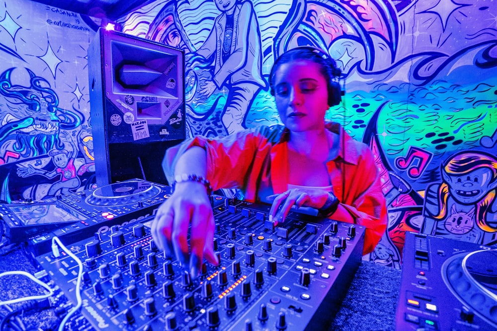 a woman mixing music in front of a colorful wall