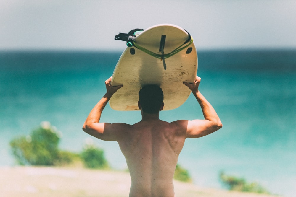 Un hombre sosteniendo una tabla de surf sobre su cabeza