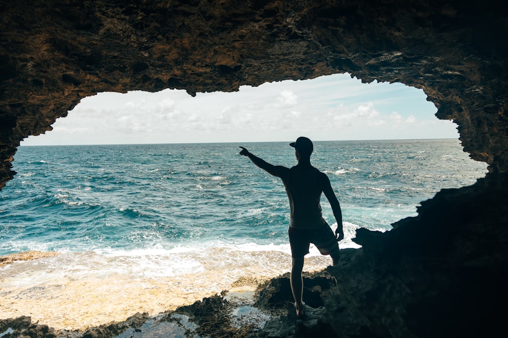 Un hombre parado en una playa rocosa junto al océano