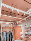 Interior view of a modern, cozy women's clothing shop with rose and white decor and happy customers browsing