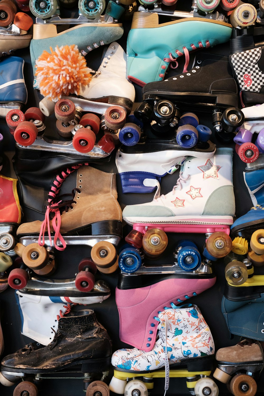 a pile of skateboards and roller skates all stacked on top of each other