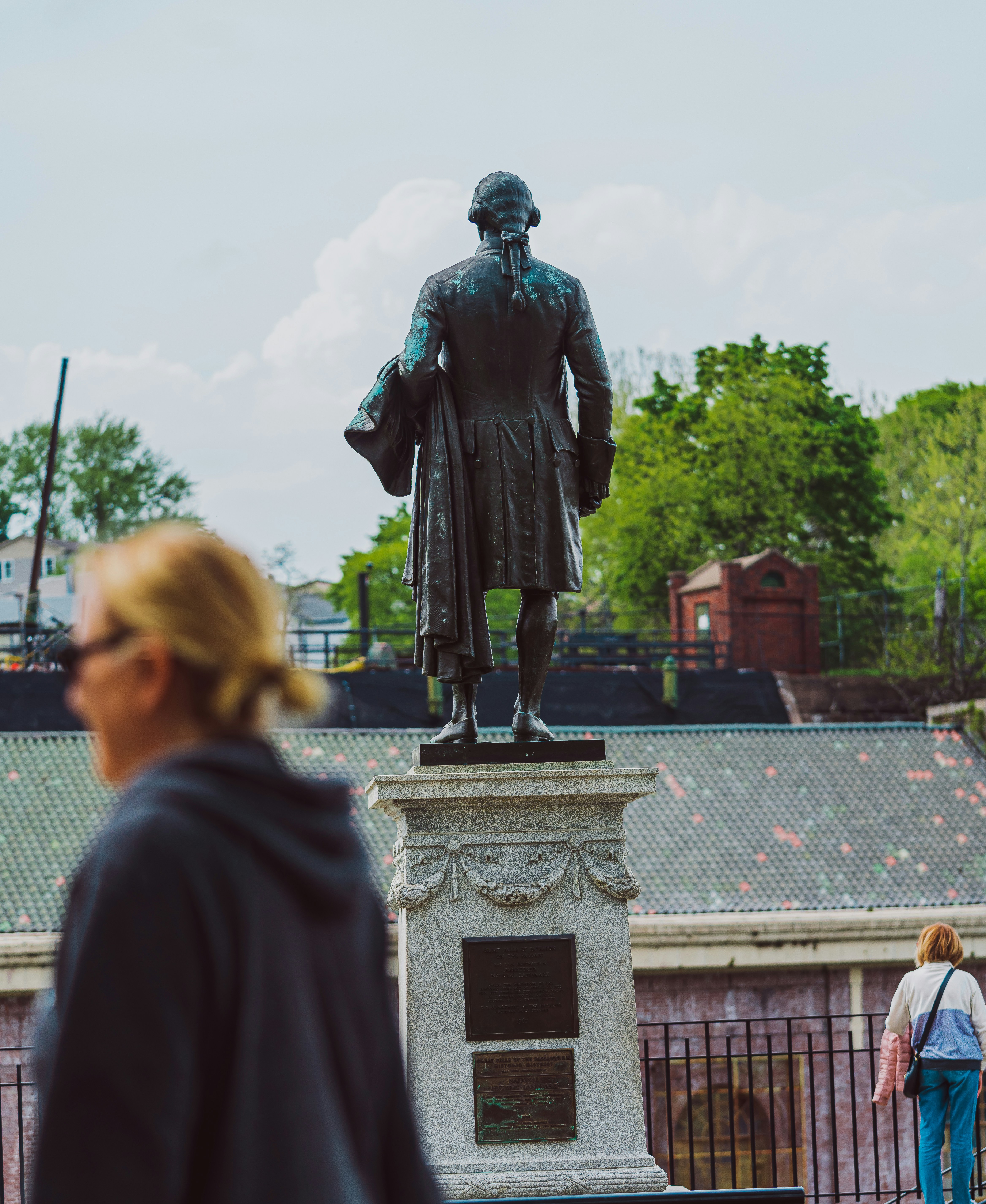 a woman walking past a statue of a man